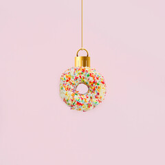 Christmas composition. Christmas ornament made of colorful doughnut on pastel pink table...