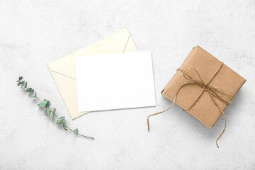 Tied box with envelope, blank card and eucalyptus on white grunge background