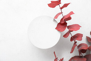 Branch with red leaves and plaster podium on white grunge background