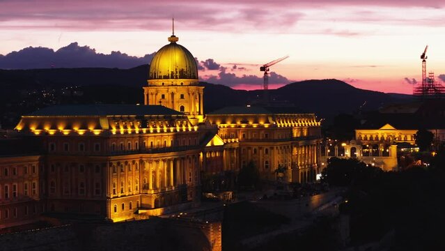 Aerial slide and pan footage of Buda Castle complex with large dome against colour twilight sky. Famous sights in evening. Budapest, Hungary