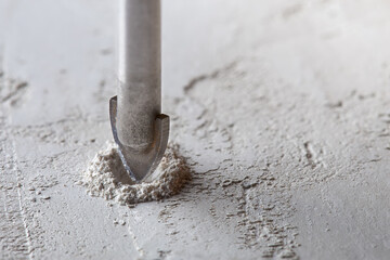metal drill bit make holes in concrete wall on industrial drilling machine with shavings. Metal...