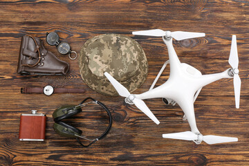 Modern quadcopter and military set on wooden background