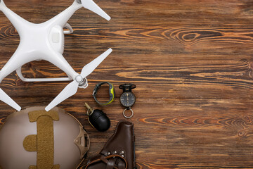 Modern quadcopter, military helmet, grenade, holster, watch and compass on wooden background