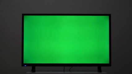 Close-up of TV screen with green background. Concept. Plasma TV screen with green screen. Modern TV on bedside table with green screen for insertion in house - Powered by Adobe