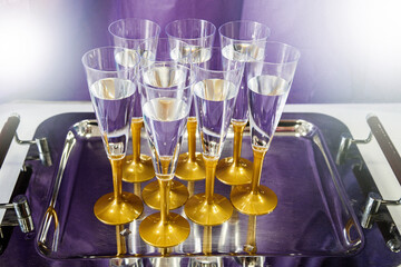 Glasses for champagne with gold color glass stem on a table in a restaurant or hotel.