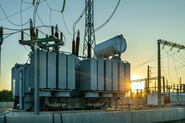 High voltage transformer in the rays of the morning sun. the result of shooting in the direction of sunrise. - obrazy, fototapety, plakaty