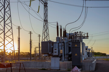 high voltage power lines with luminous wires against the background of the morning sky, sunrise over the horizon.