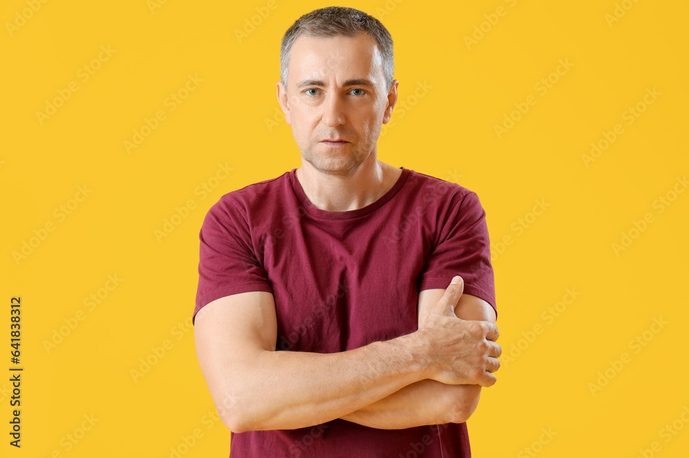 Wall mural portrait of mature man with crossed arms on orange background