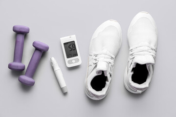 Glucometer, sneakers, lancet and dumbbells on grey background. Diabetes concept