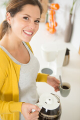 woman with a jug and cup of coffee at home