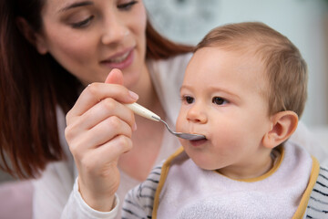 a mother feeds baby in the kitchen with baby food