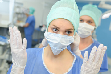 portrait of female surgeon showing surgical gloves in operation room