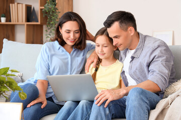 Fototapeta premium Happy family with laptop resting on sofa in living room