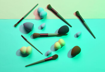 Makeup sponges and brushes on turquoise background