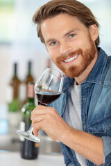 man tasting a glass of red wine at home