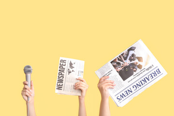 Female hands with microphone and newspapers on color background