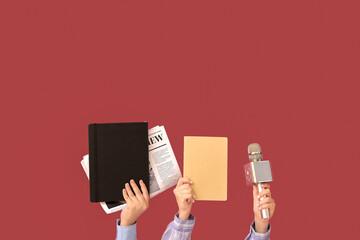 Female hands with notebooks, newspaper and microphone on color background