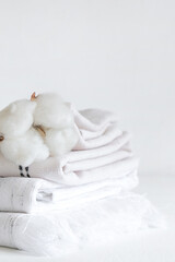 Cotton branch with pile of folded bed sheets and blankets.Organic lifestyle and skin care products.