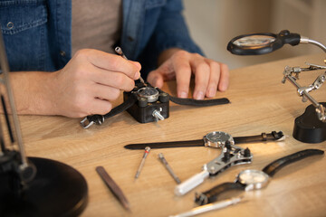 hands holding tweezers repairing vintage clocks