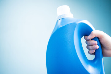Hand holding a blue liquid soap bottle on blue background