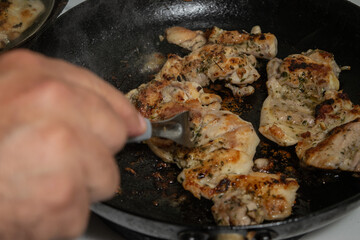 Professional Chef in a Modern Kitchen Cooking a Mouthwatering Chicken Dish with Fresh Herbs and Spices