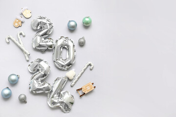 Figure 2024 made of balloons with Christmas decorations on grey background