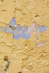 Yellow wall with cracks and peeling paint in grunge