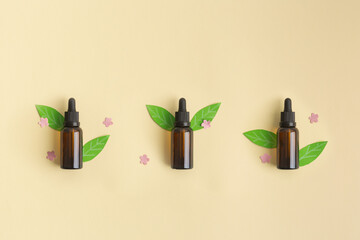Bottles of essential oil flatlay concept with leaves and littles flowers cut from paper and real...