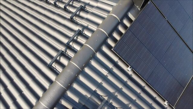 Drone flight over roof with solar panels ending up on electric car charging with solar electricity .
