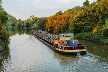 Transportation industry. Ship barge transports scrap metal and sand with gravel. Barge loaded with scrap metal is on the roadstead. Scrap metal transportation by water. Barge laden by metal salvage