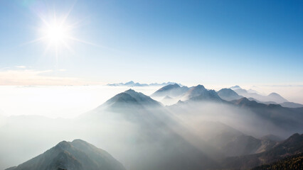 Astonishing scene of mountain range horizon in the morning mist, illuminated by the light of the...