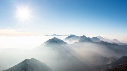 Astonishing scene of mountain range horizon in the morning mist, illuminated by the light of the rising sun, aerial shot. The majestic beauty of nature concept.