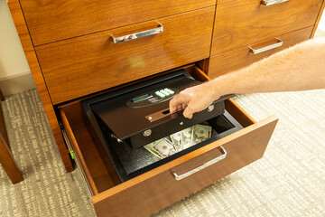 Person retrieving valuables from safe in hotel room.