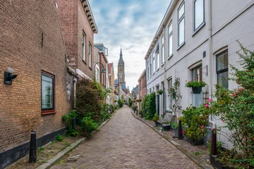 Fotobehang Picturesque Delft cityscape with a view through a narrow ancient alley on the tower of the famous Nieuwe Kerk. Delft, the Netherlands. Old alley called The Trompet Straat © FotoCorn