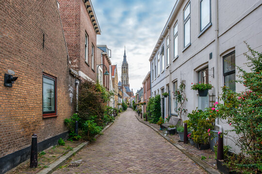 Picturesque Delft cityscape with a view through a narrow ancient alley on the tower of the famous Nieuwe Kerk. Delft, the Netherlands. Old alley called The Trompet Straat