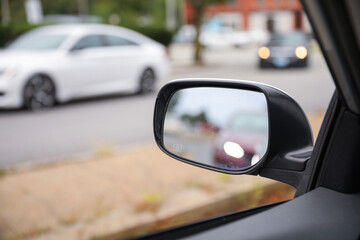 Car mirror reflects paths behind, a symbol of retrospection, foresight, and self-awareness,...