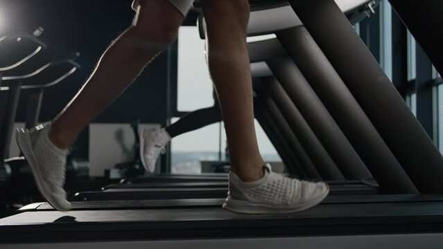 Sports shoes woman and man muscular legs feet run on treadmill workout at gym jogging sneakers running on treadmill cardio exercises couple of runners active sport people training jog in fitness club