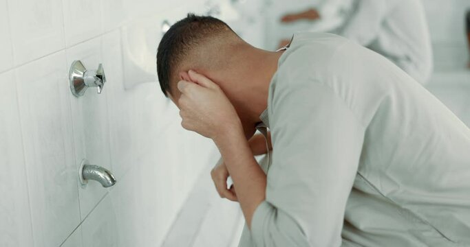 Muslim, religion and man ear washing for prayer in bathroom for purity, and cleaning ritual. Islamic, worship and faith of group of people with wudu together at a mosque or temple for holy practice