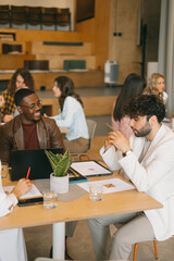 White businessman cannot figure it out a simple thing. He looks confused. Black male person laughing at him