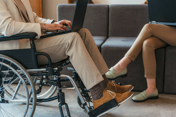 Disabled employee in wheelchair. Woman sitting on sofa. Businesspeople working together. Cropped photo