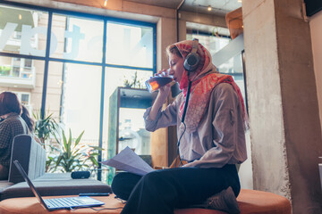 Muslim businesswoman drinking juice, refreshment, while analyzing some reports at work