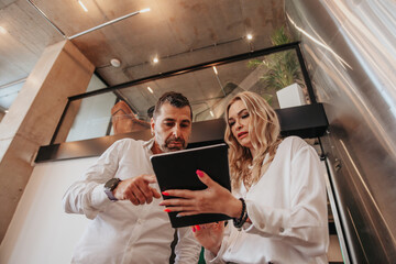 Middle-aged, blonde businesswoman discussing teamwork statistics with her male business partner....