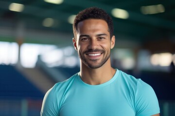 Fototapeta premium An athlete of Middle Eastern descent wearing a Polo in a bright turquoise hue standing still against a hazy sports arena background.