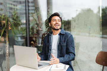 Handsome Indian man, freelancer, programmer using laptop computer