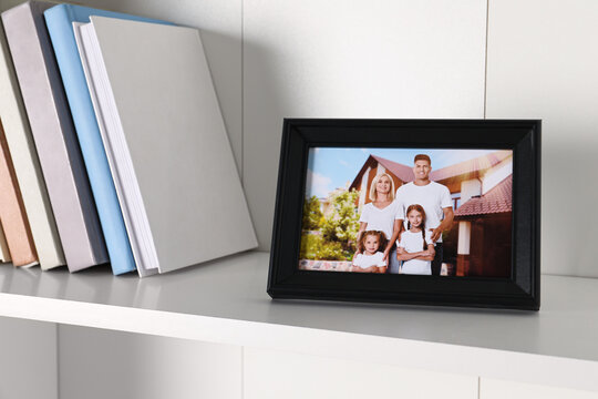 Frame with family photo and books on shelf indoors