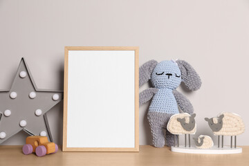 Empty square frame and different toys on wooden table