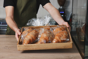 Seller with croissants at cashier desk in bakery shop, closeup