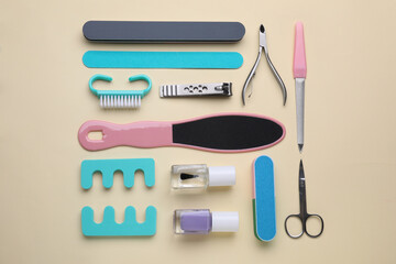 Set of pedicure tools on beige background, flat lay