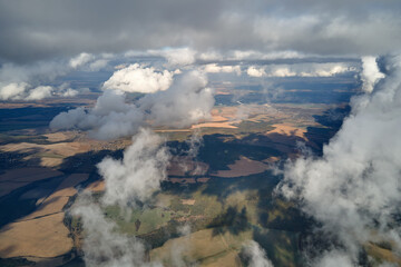 Aerial view at high altitude of earth covered with puffy cumulus clouds forming before rainstorm