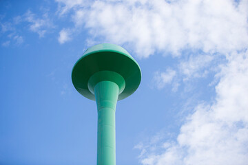 Water tower with blue sky and white clouds, closeup of photo